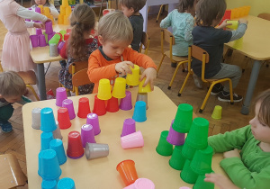 dzieci budują wieże z kolorowych kubeczków.